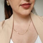 Imagem mostrando uma modelo usando o colar veneziana da loja online Céu da Pele, combinando com um brinco orgânico também disponível na loja.
