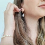 Imagem mostrando uma mulher usando brinco com pérola disponível na loja online de semijoias Céu da Pele.